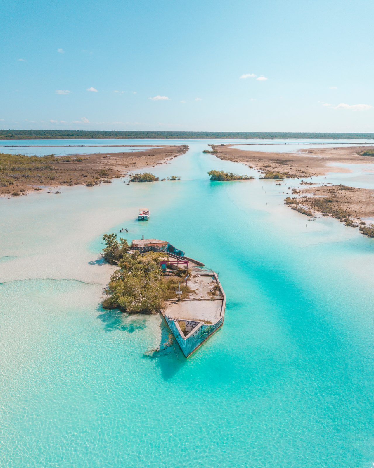 The half-sunken 'pirate ship' islet rising from the shallows along a turquoise channel